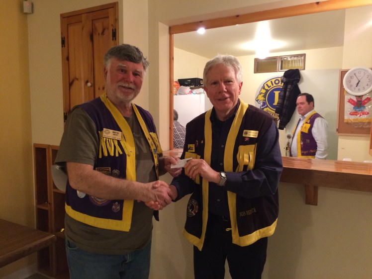 Lion Bob Reddick (right) presents Lion President Wayne Bent with the Silver Centennial Lion pin for recruiting and retaining new Lions for 2017.